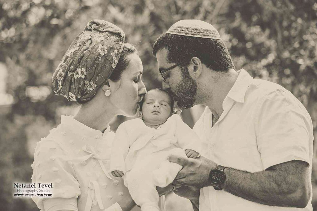 הורים מנשקים תינוק משני צידיו בברית המילה